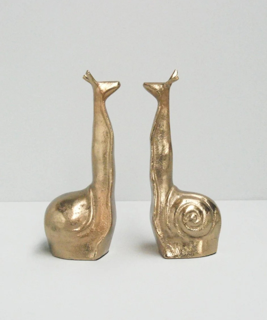 White Moose snail-shaped gold bookends with a sleek, modern design for organizing books on a shelf.