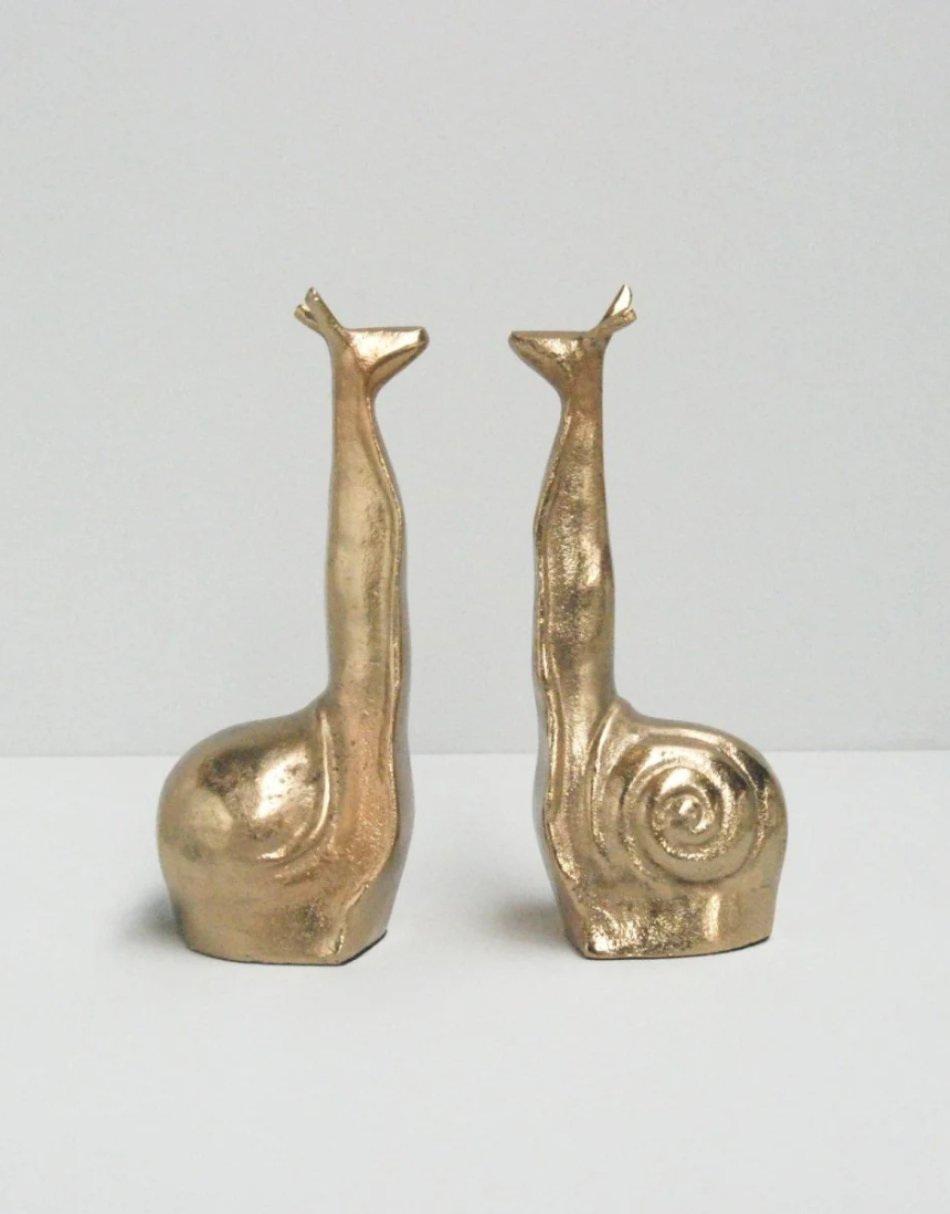 White Moose snail-shaped gold bookends with a sleek, modern design for organizing books on a shelf.