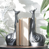 White Moose snail-shaped black bookends, decorative and functional for holding books upright on a shelf.