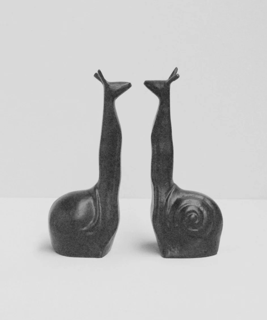 White Moose snail-shaped black bookends on a shelf, decorative and functional for holding books upright.