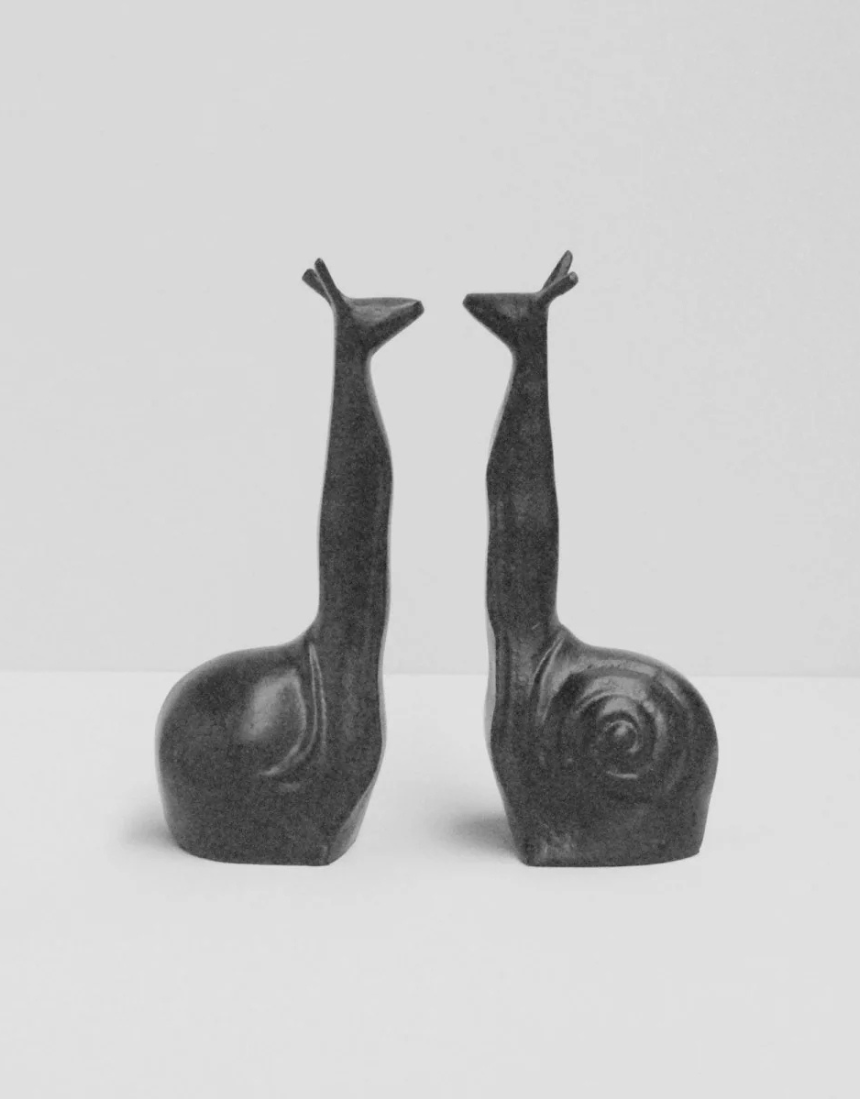 White Moose snail-shaped black bookends on a shelf, decorative and functional for holding books upright.