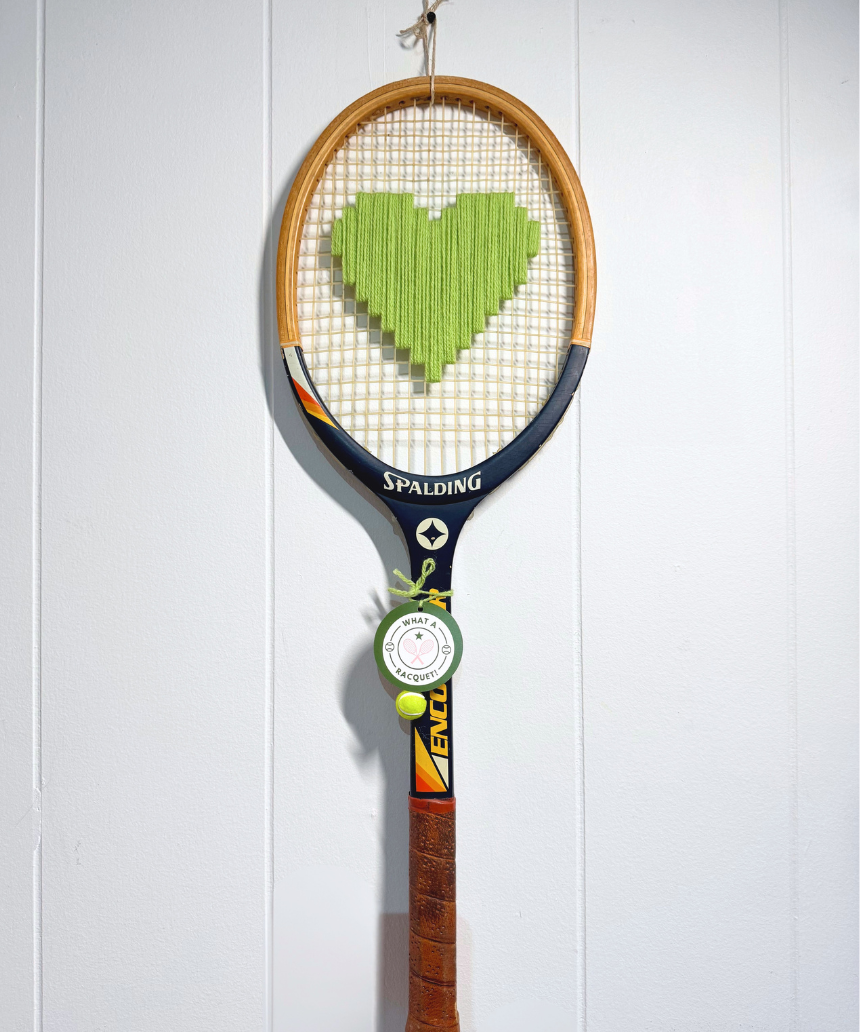 Apple green heart-shaped tennis racquet by What A Racquet! with a sleek, vibrant design and a comfortable grip.