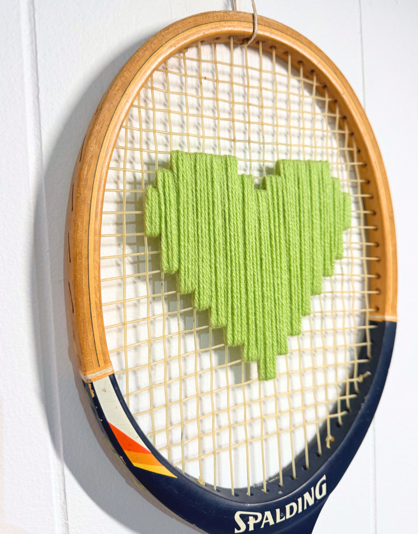 Apple green heart-shaped tennis racquet from What A Racquet! with a sleek, vibrant design and smooth handle grip.