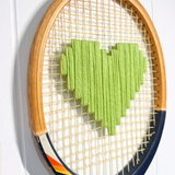 Apple green heart-shaped tennis racquet from What A Racquet! with a sleek, vibrant design and smooth handle grip.