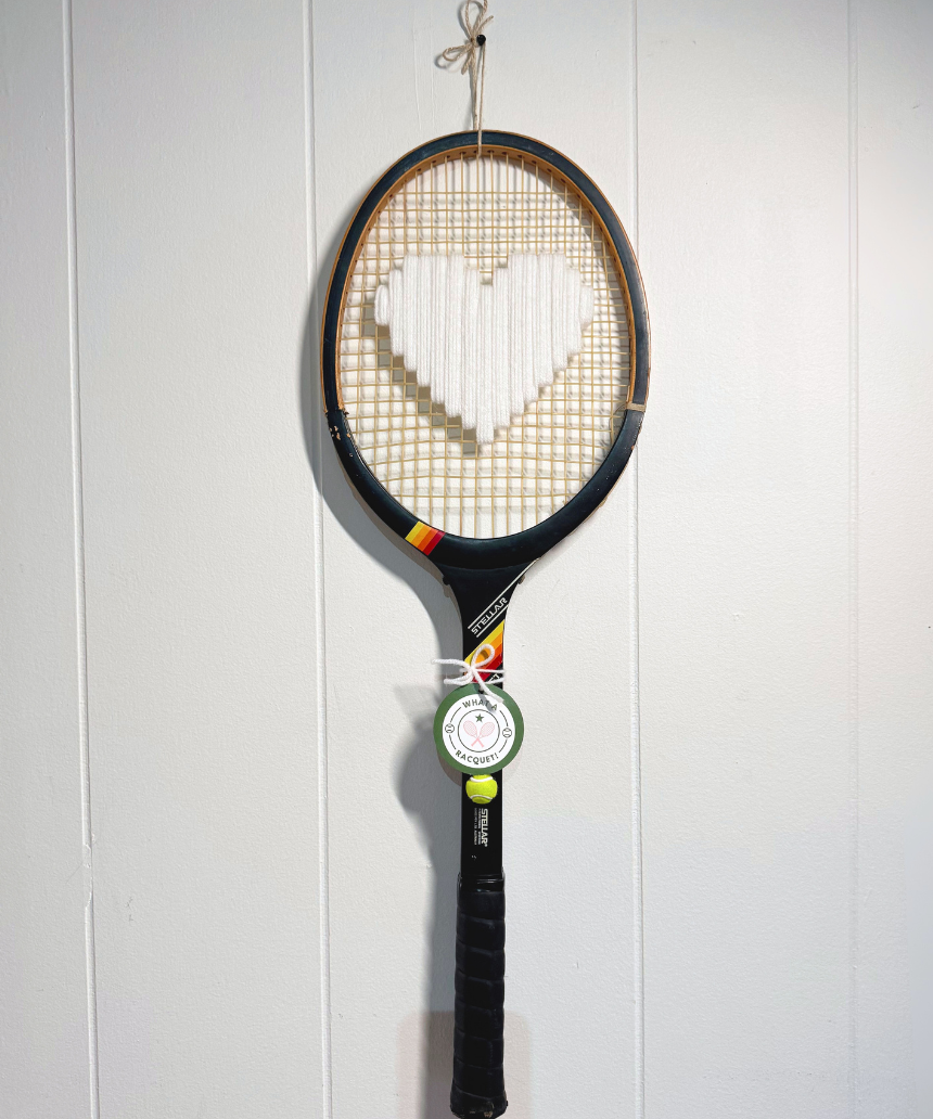 White heart-shaped tennis racquet by What A Racquet! with a black frame, featuring a sleek, modern design.