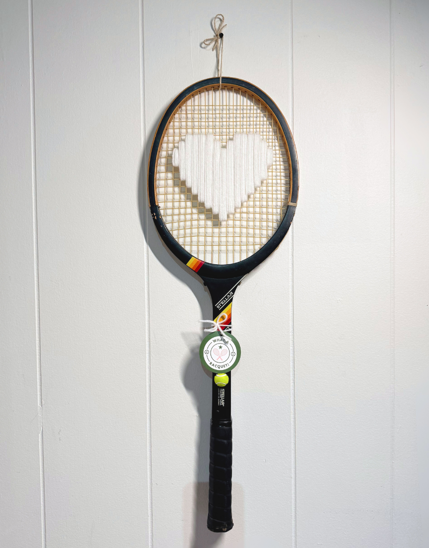 White heart-shaped tennis racquet by What A Racquet! with a black frame, featuring a sleek, modern design.