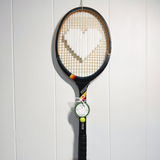White heart-shaped tennis racquet by What A Racquet! with a black frame, featuring a sleek, modern design.