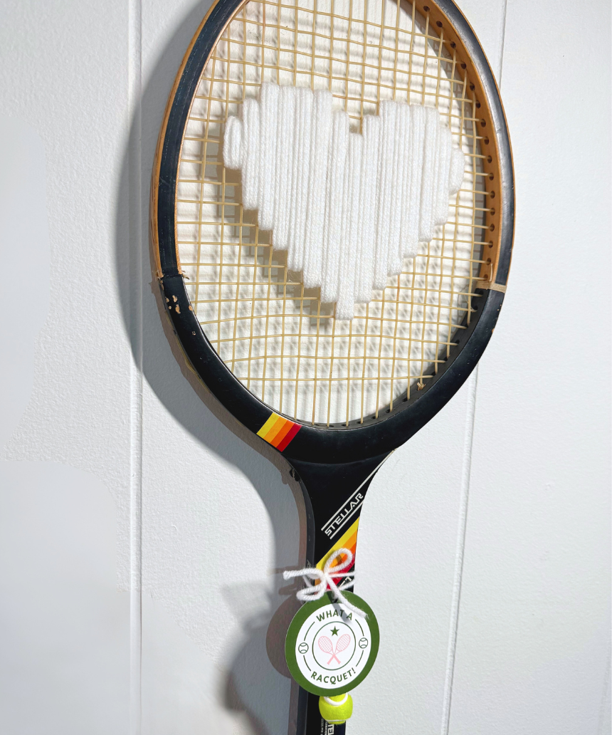 White heart-shaped racquet by What A Racquet! with a black frame, featuring a sleek design and comfortable grip.