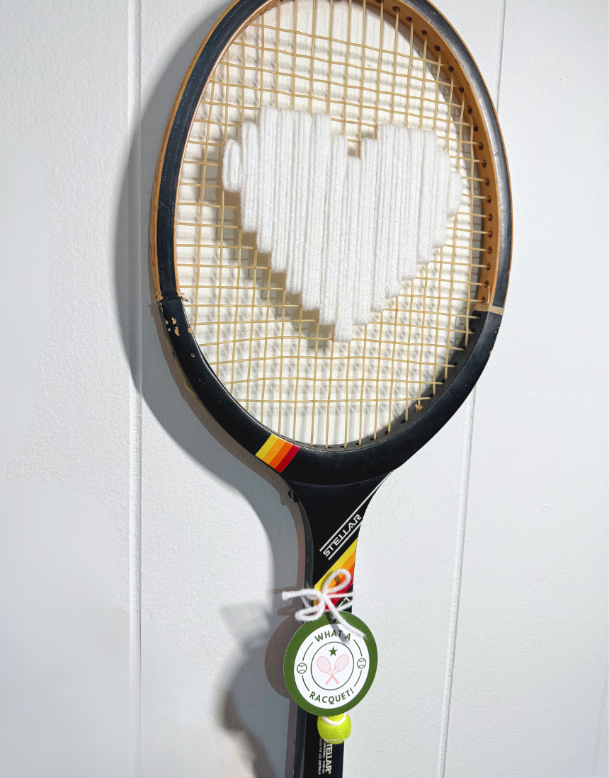 White heart-shaped racquet by What A Racquet! with a black frame, featuring a sleek design and comfortable grip.