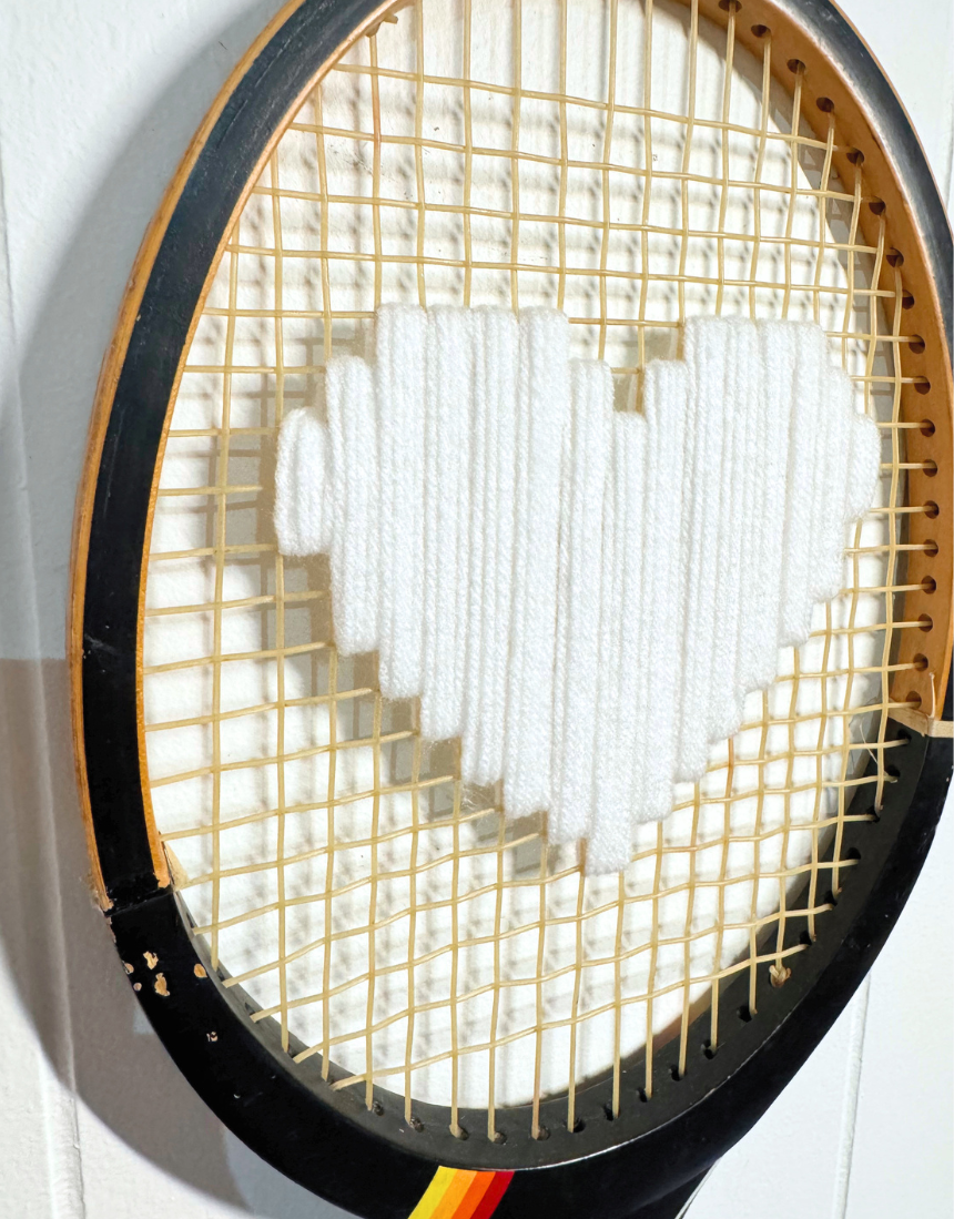 What A Racquet! white heart tennis racquet with black frame, showcasing the stylish design and grip details.