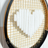 What A Racquet! white heart tennis racquet with black frame, showcasing the stylish design and grip details.