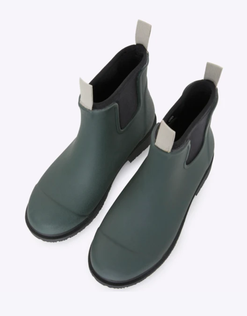 Forest green Merry People Bobbi gumboots shown on a person, featuring glossy waterproof rubber and sturdy soles.