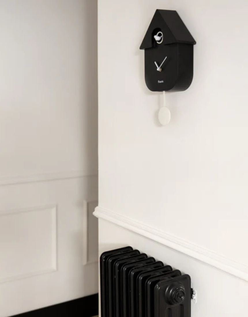 Fisura Casita Black cuckoo clock with a charming house design and traditional clock face, hanging on a wall.