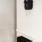 Fisura Casita Black cuckoo clock with a charming house design and traditional clock face, hanging on a wall.
