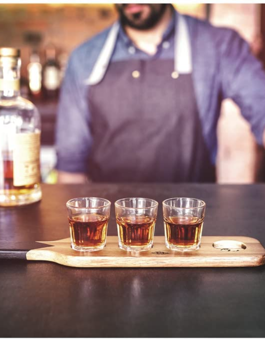 Gentlemen's Hardware shot glasses on a wooden serving paddle, ready for drinks, with a rustic, adventure-inspired design.