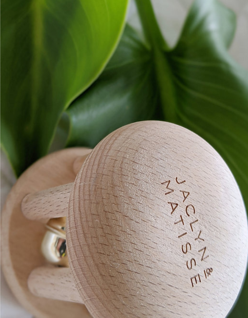 Wooden rattle toy named Bella the Bell by Jaclyn and Matisse, designed for infants with colorful, child-friendly features.
