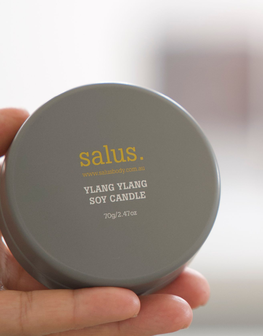 Salus Ylang Ylang Travel Soy Candle showing a small glass jar with a lit candle and floral Ylang Ylang scent.