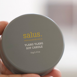 Salus Ylang Ylang Travel Soy Candle showing a small glass jar with a lit candle and floral Ylang Ylang scent.